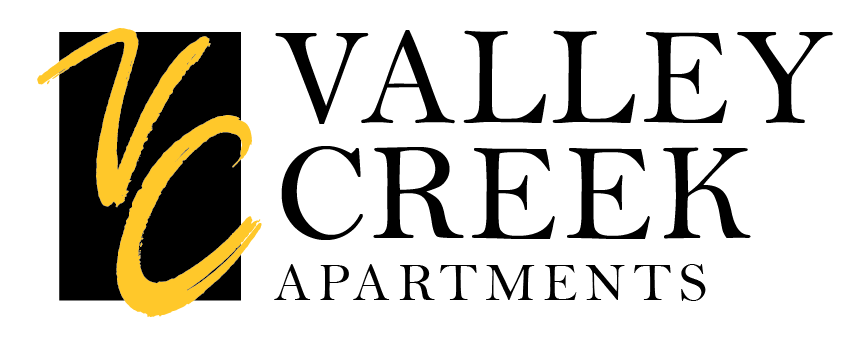 A black and gold logo for Valley Creek Apartments.
